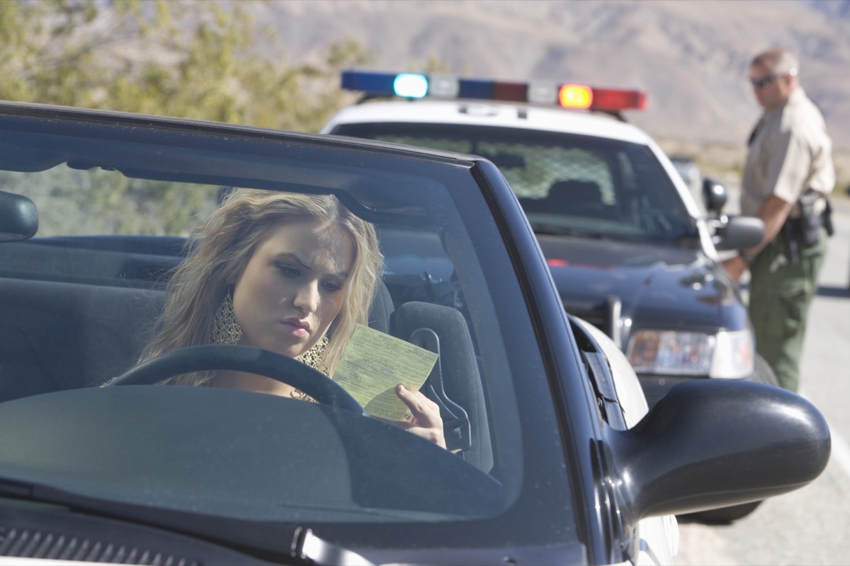 pulled over woman looking at traffic ticket things you should never do when getting pulled over