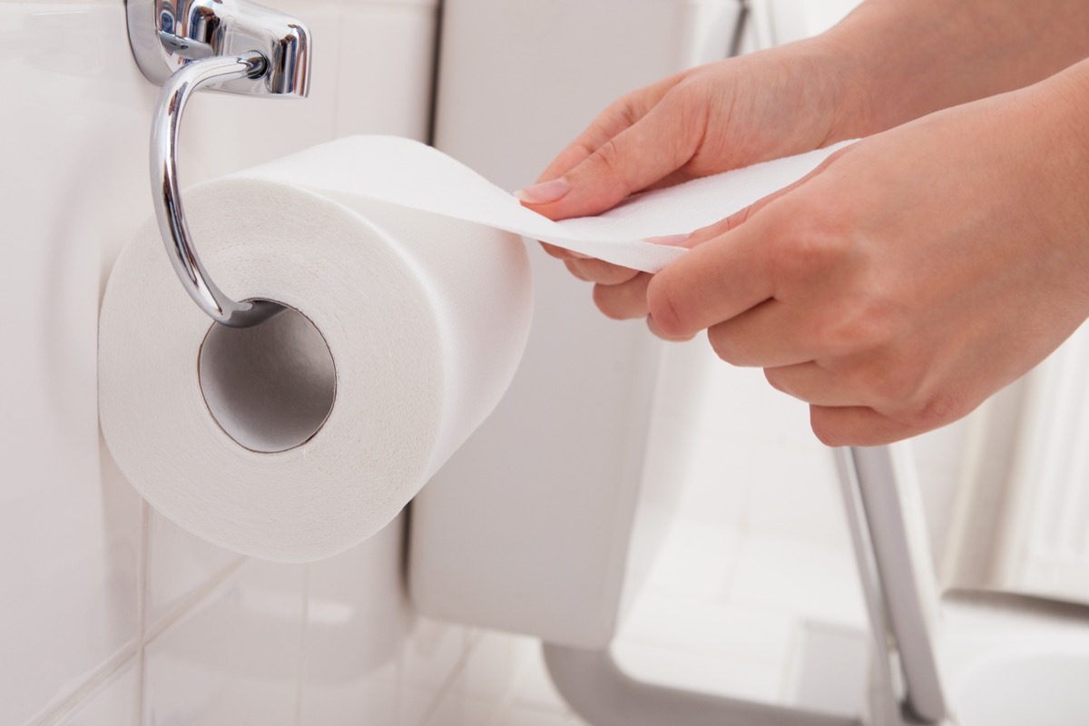 Person's Hand on a Roll of Toilet Paper