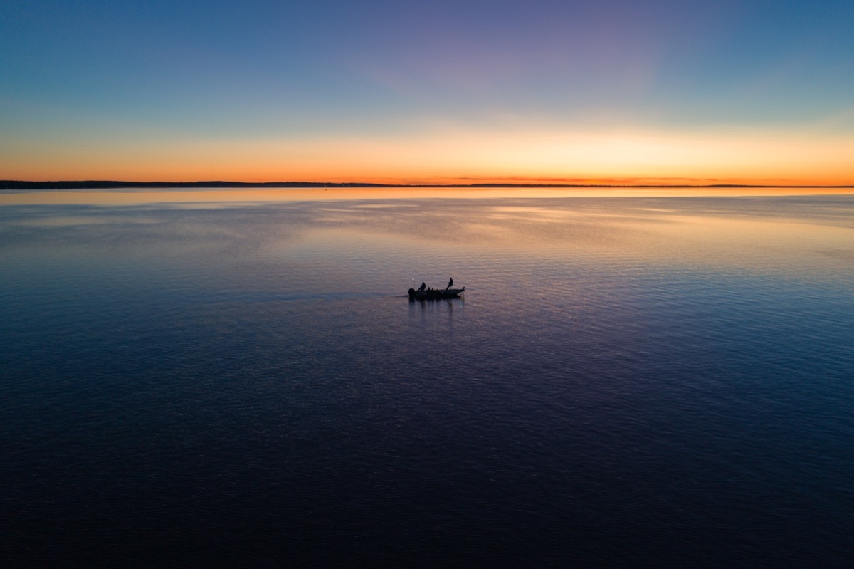 A small fishing boat on Houghton Lake at sunrise, state fact about michigan