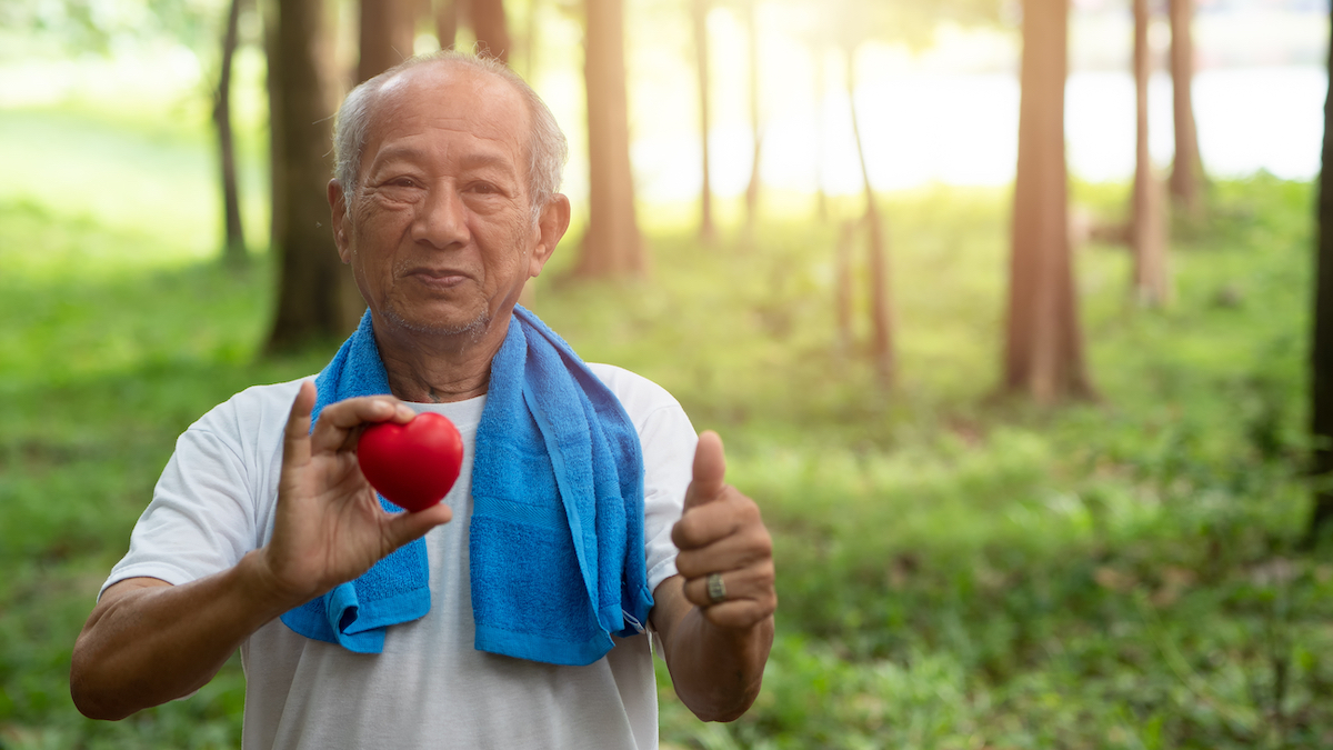 Asian man holding a heart outside