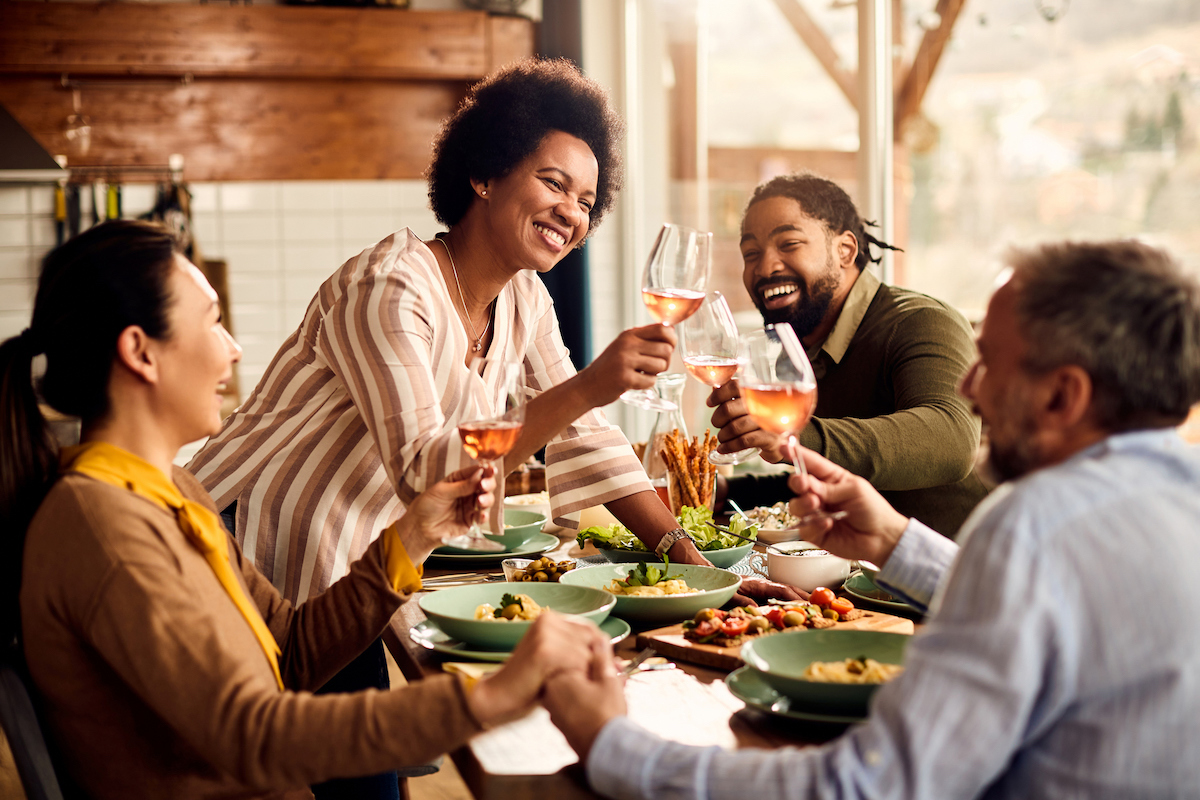 Group of friends toasting with rose wine at the dinner table