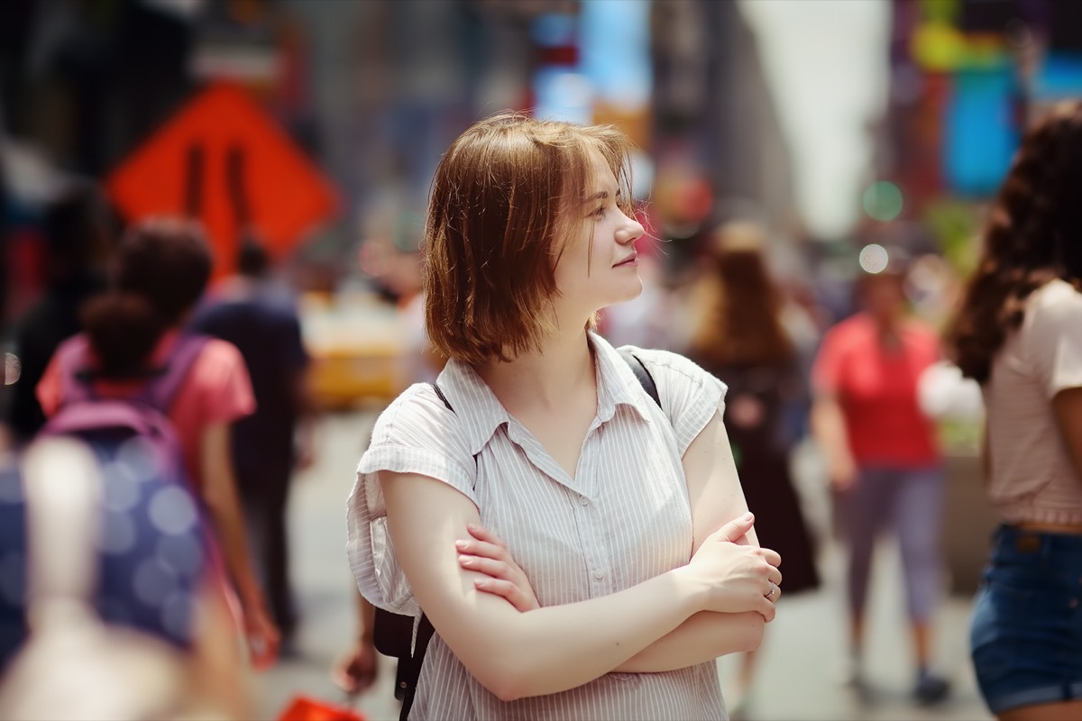 Charming young woman tourist looking on Times Square on sunny summer day, downtown Manhattan