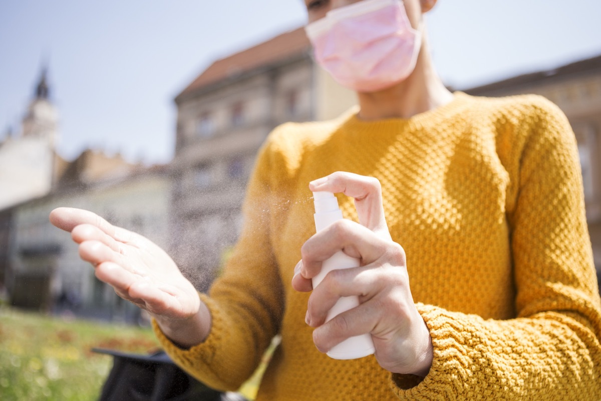 Cleaning hands with sanitizer spray in city