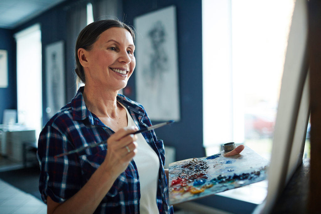 woman in her 50s happily painting