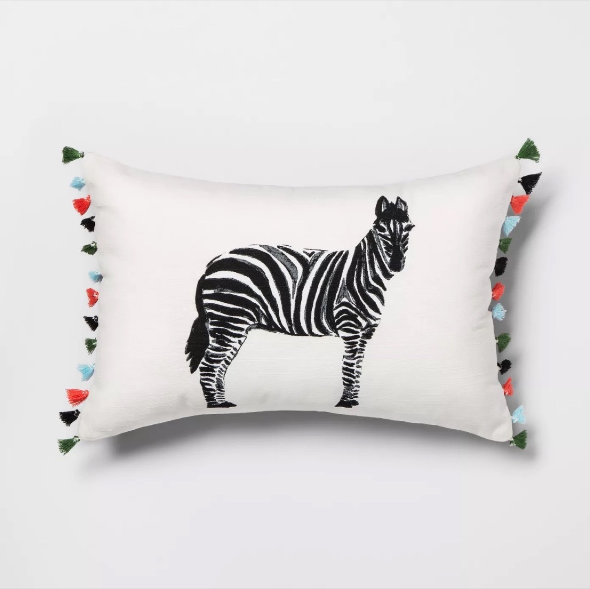 white throw pillow with zebra in the center and multicolored tassels