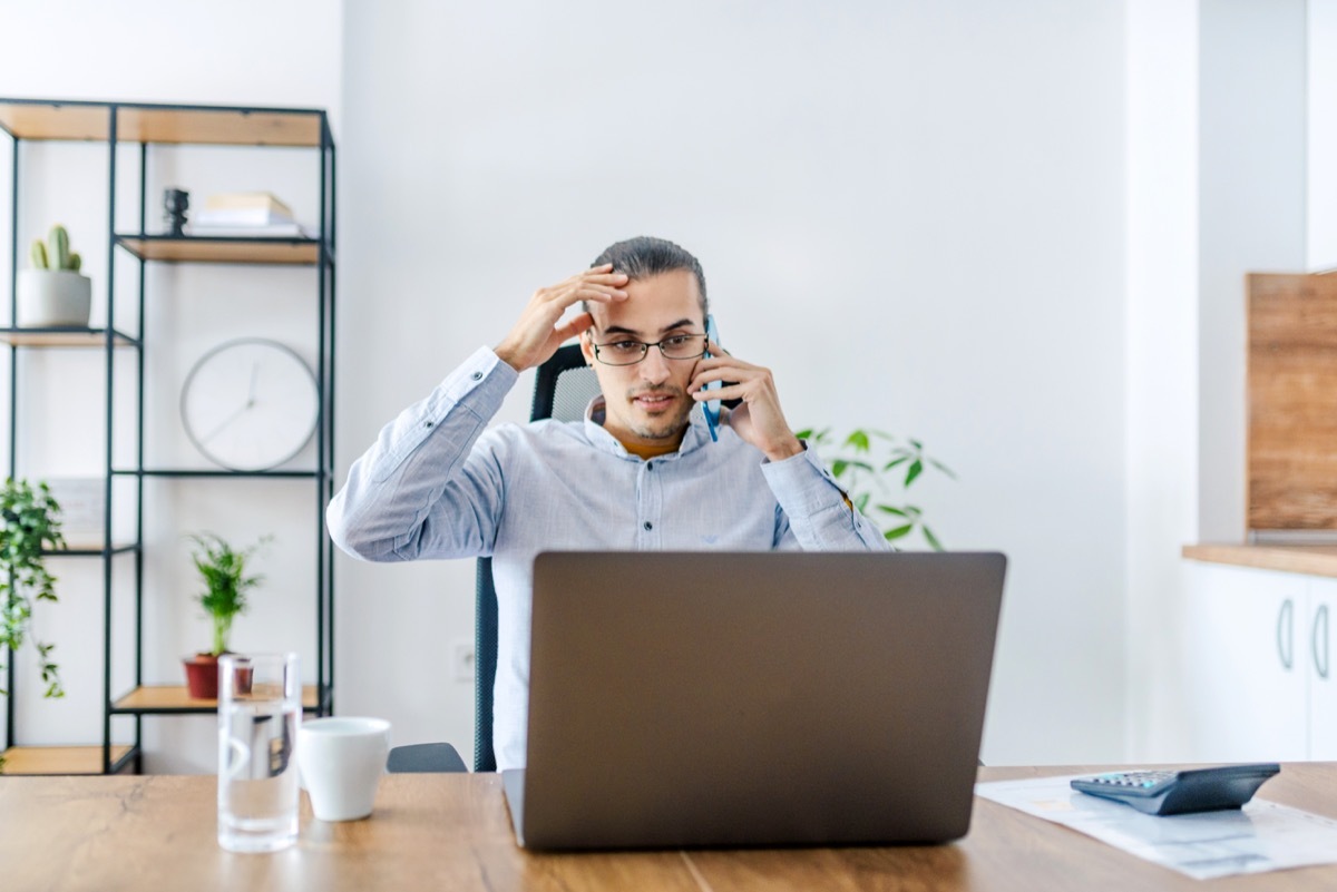 man working on a laptop. Home office / Work from office concept. Portrait of a worried / anxious businessman working remotely on his laptop.