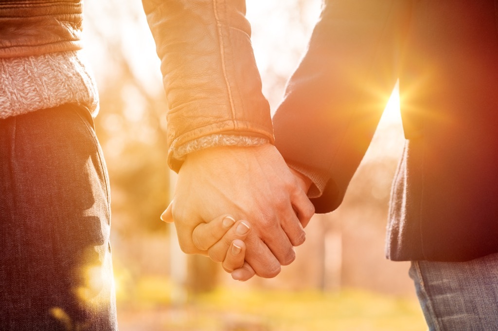 A couple holding hands outside. 