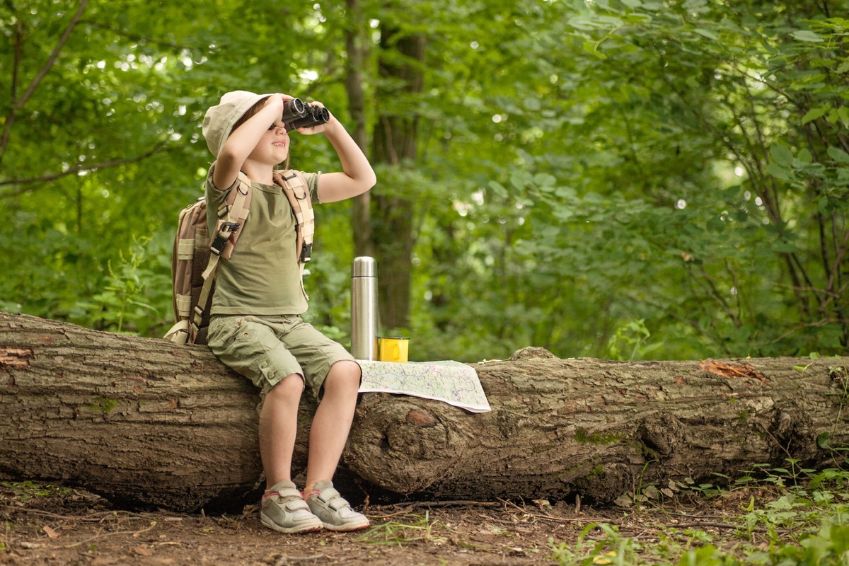 excited little girl on a camping trip in green forest