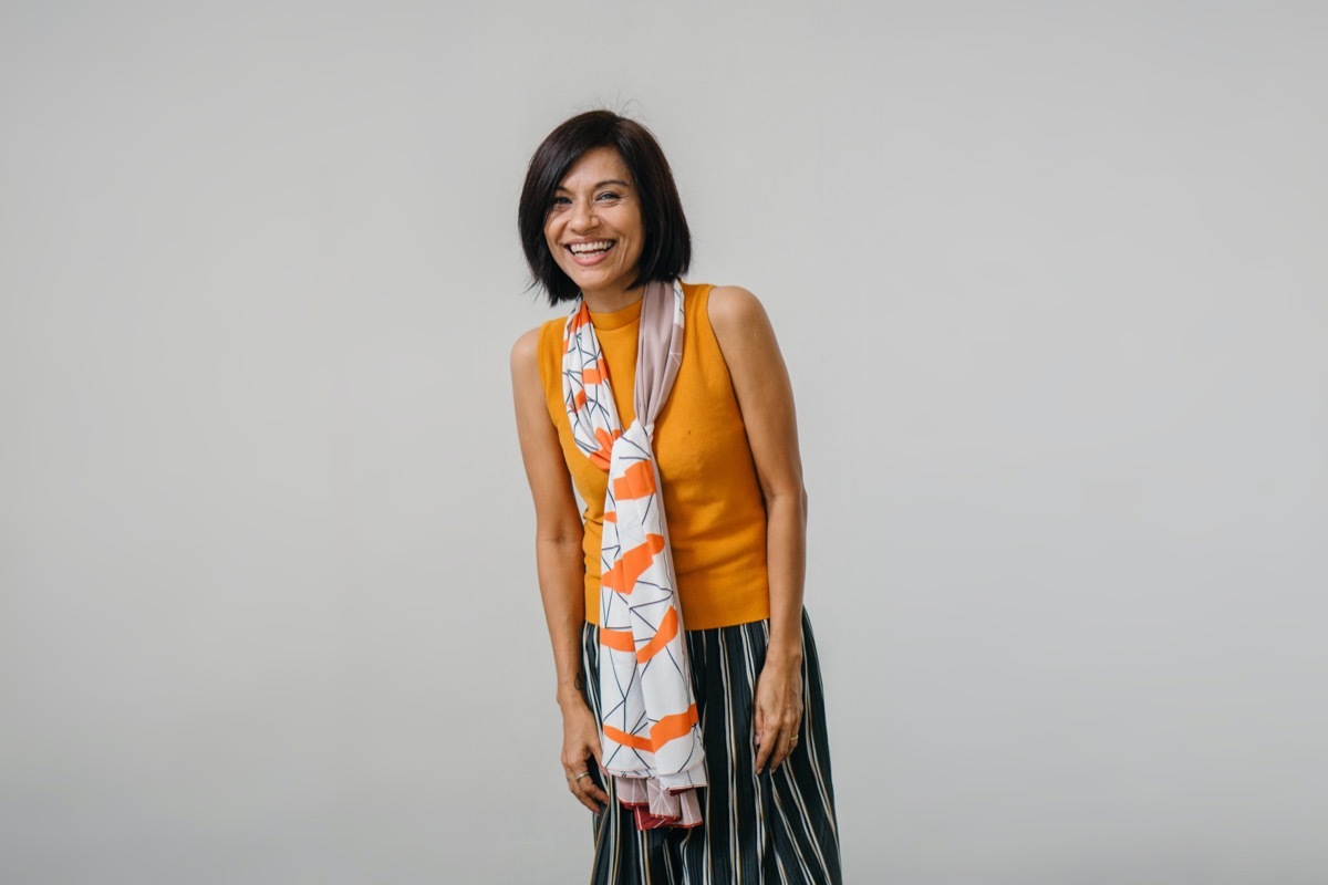 middle aged asian woman in sleeveless yellow top, scarf, and long skirt