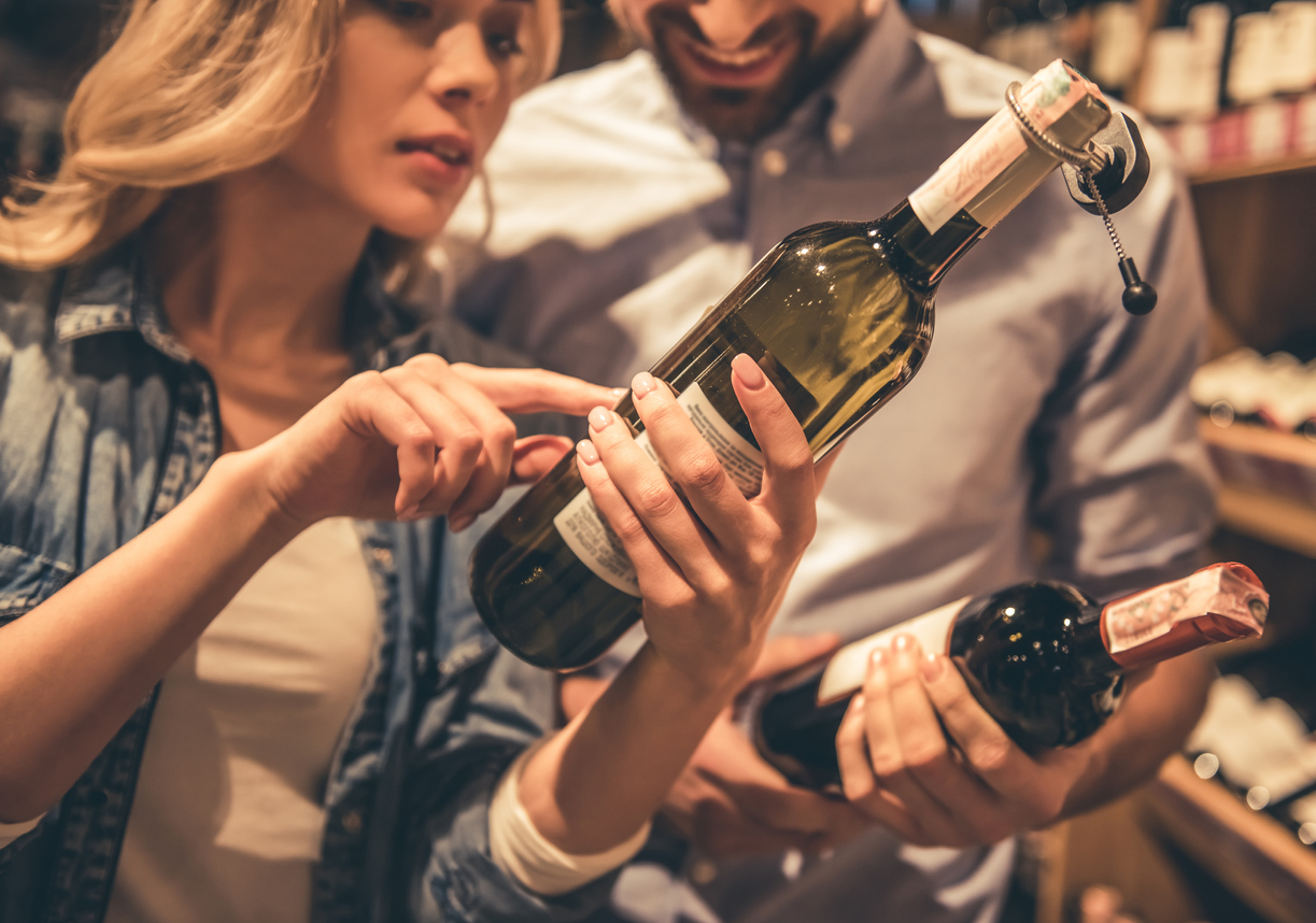 Couple looking at bottles of wine. 