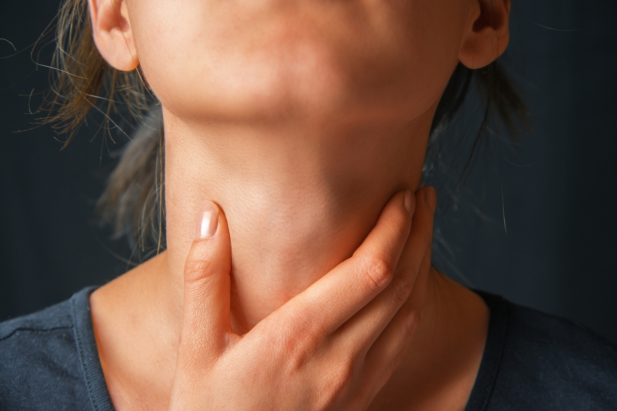 Woman with her hand on her throat.