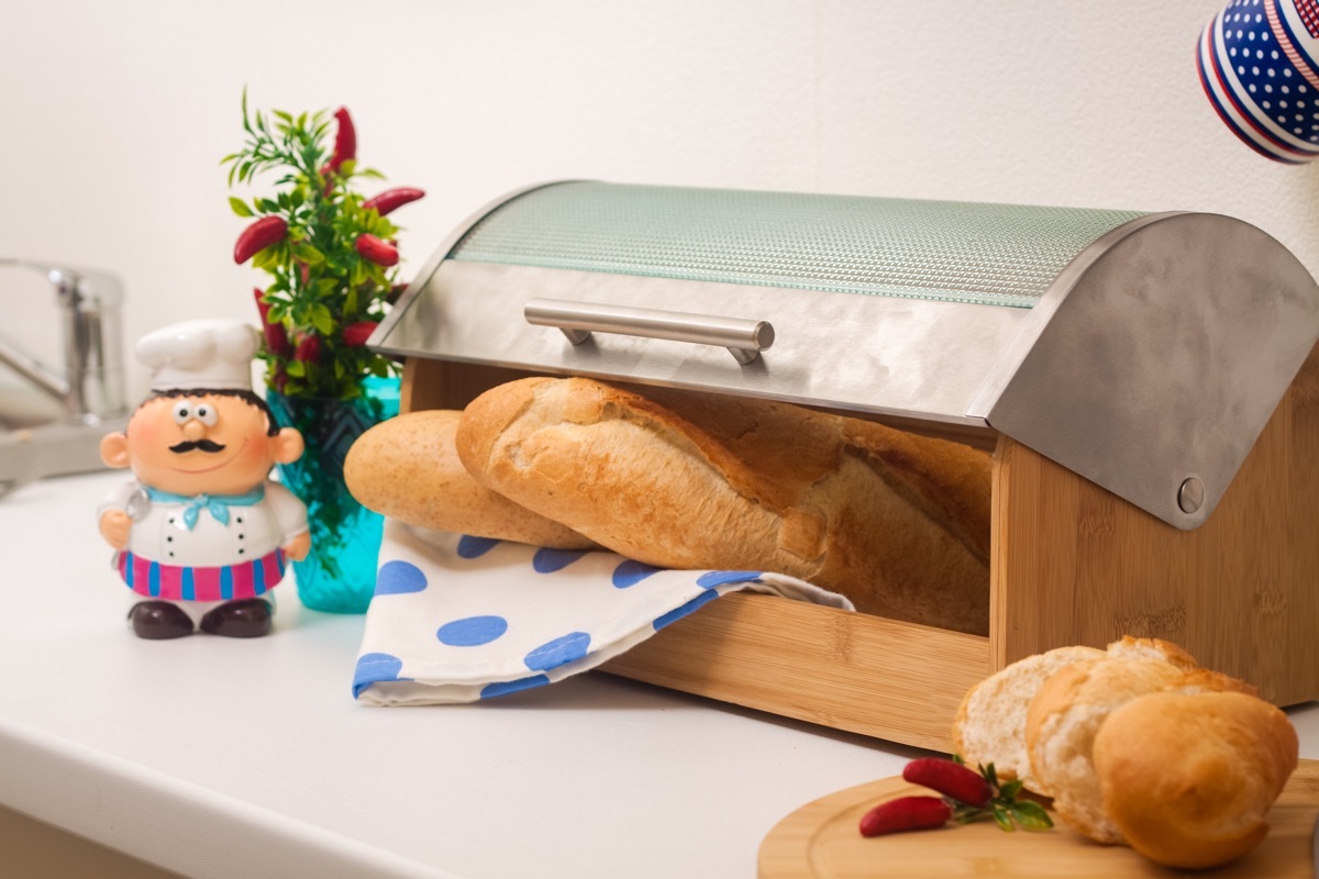 Baguette, lying in a breadbox, made of wood with metal lid