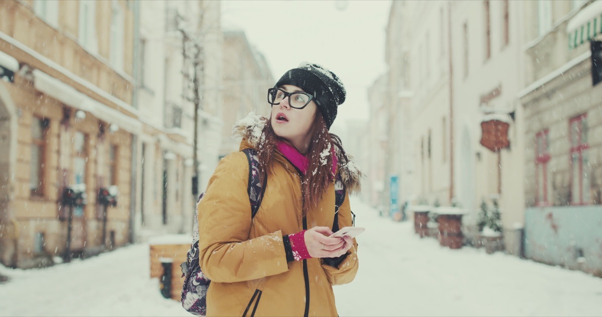 Woman confused lost walking through snow with phone