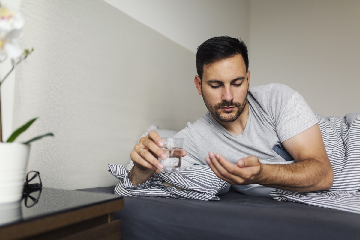 Man taking pills in bed