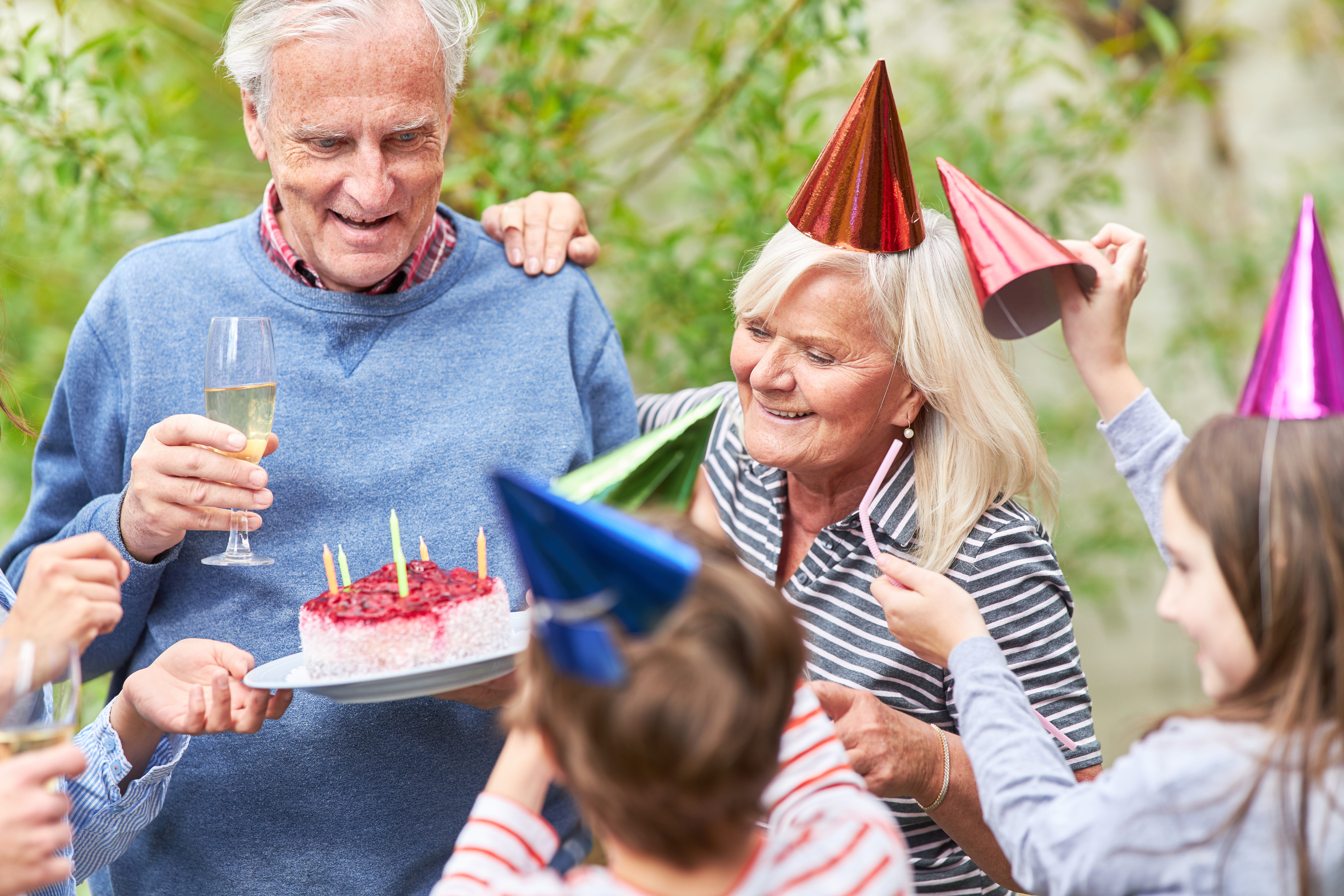 older man holding a glass of champaign and a birthday cake