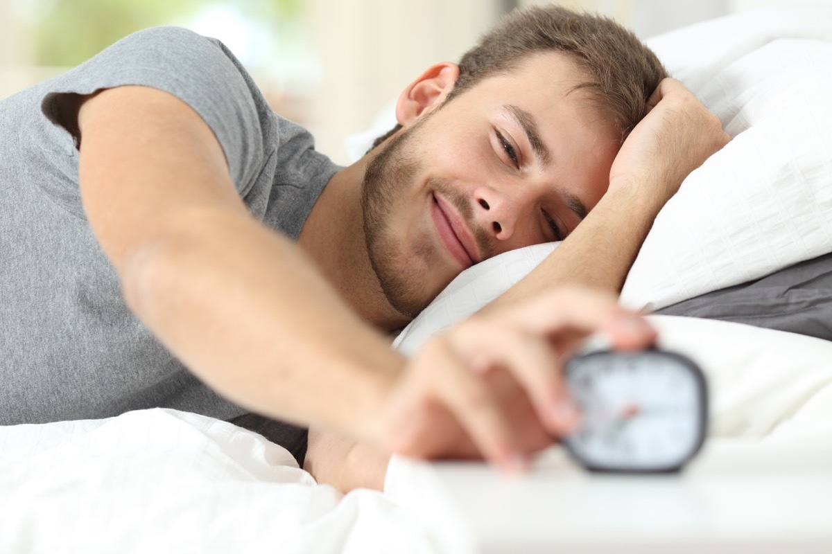 Man turning off his alarm clock