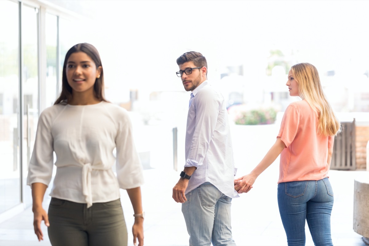 young white guy checking out woman while walking with girlfriend