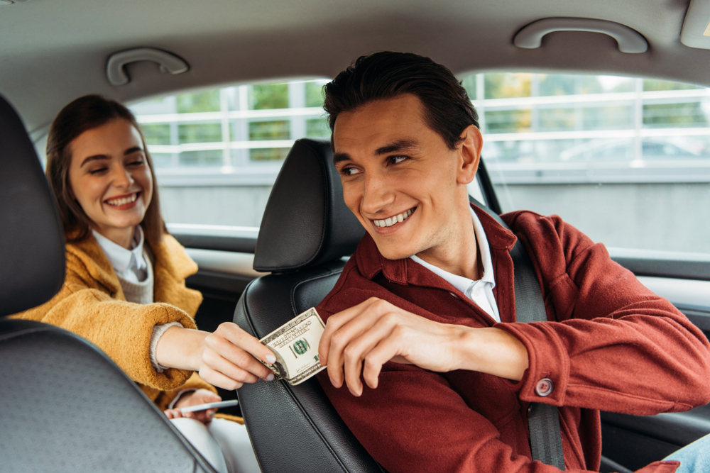 A passenger tipping or paying a taxi driver from the back seat