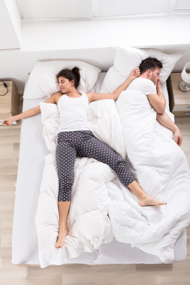 Overhead View Of Young Woman Sleeping Beside Her Husband On Bed