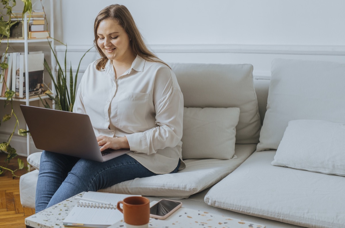 Smiling businesswoman sitting in the living room and working on her laptop computer.