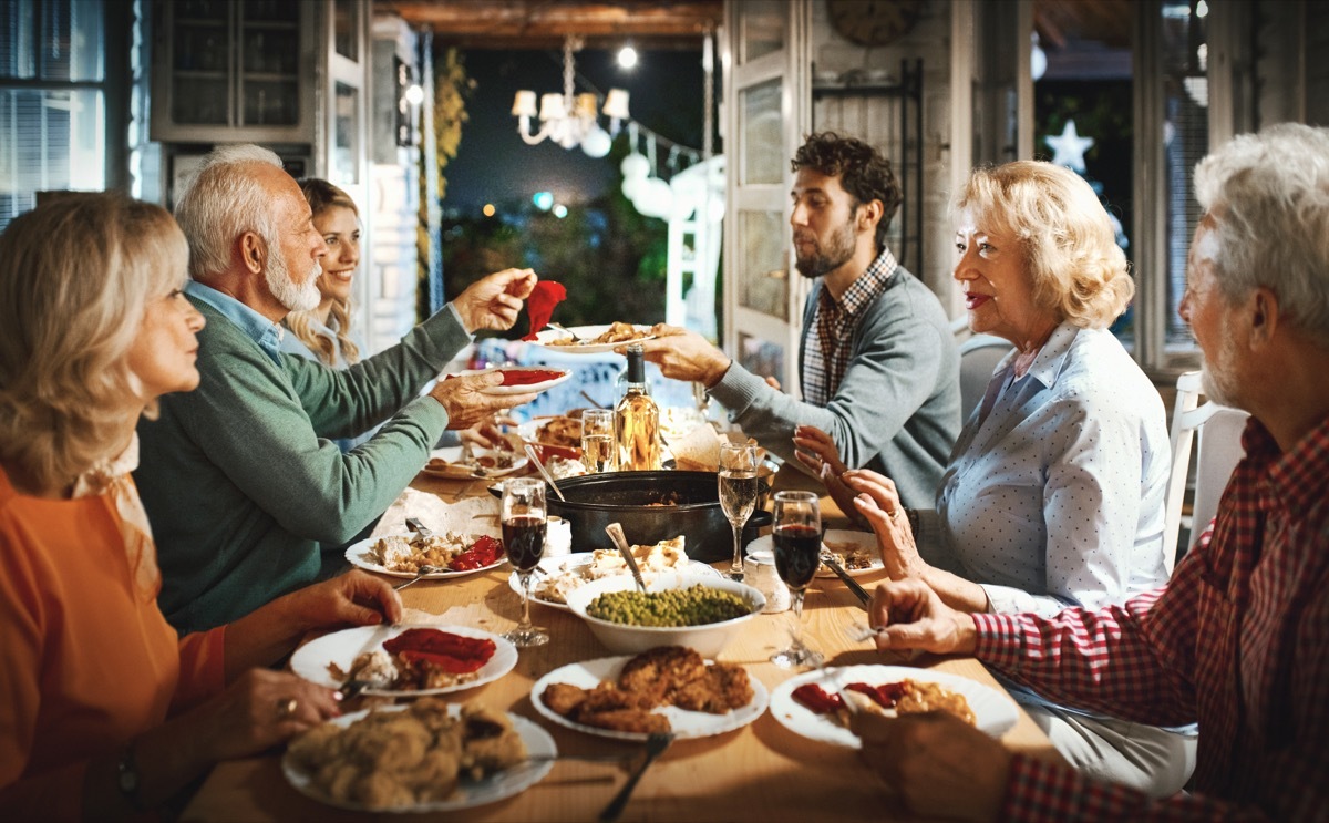 Closeup of multi generation family having Thanksgiving dinner. There are two senior couple and a mid 20's couple having a big feast, sharing food and love.