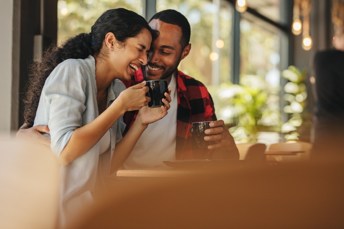 couple laughing at a cafe over good morning text for her