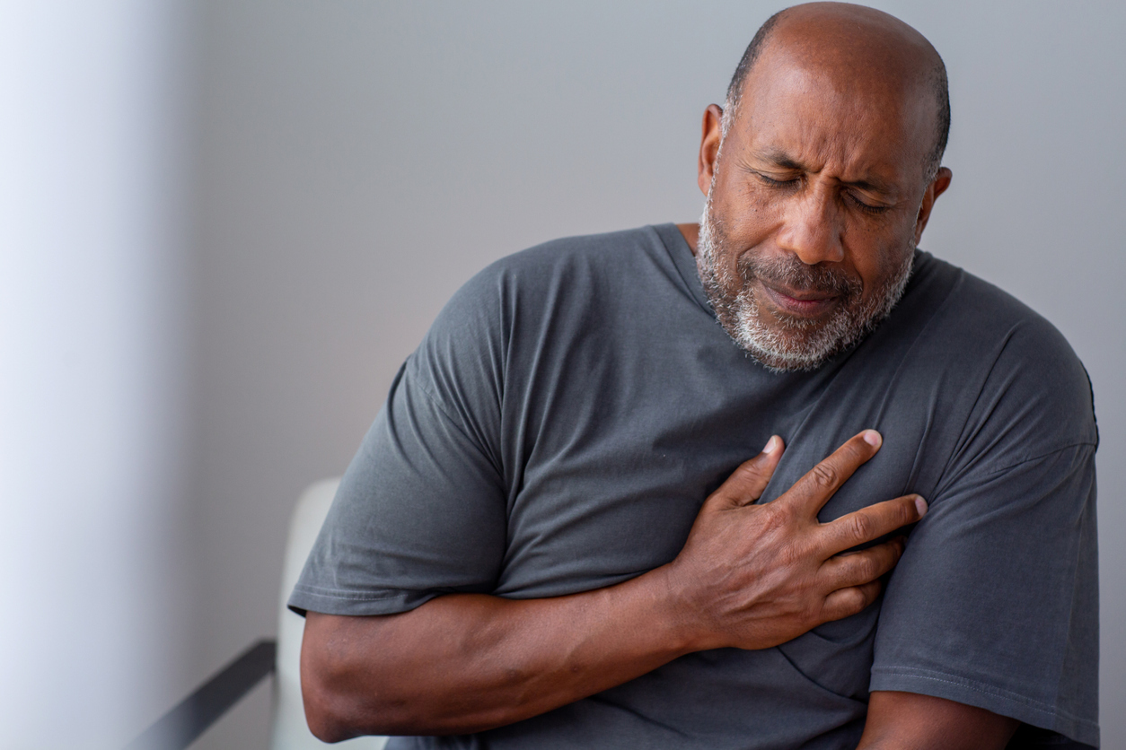 A man in pain, holding his chest.