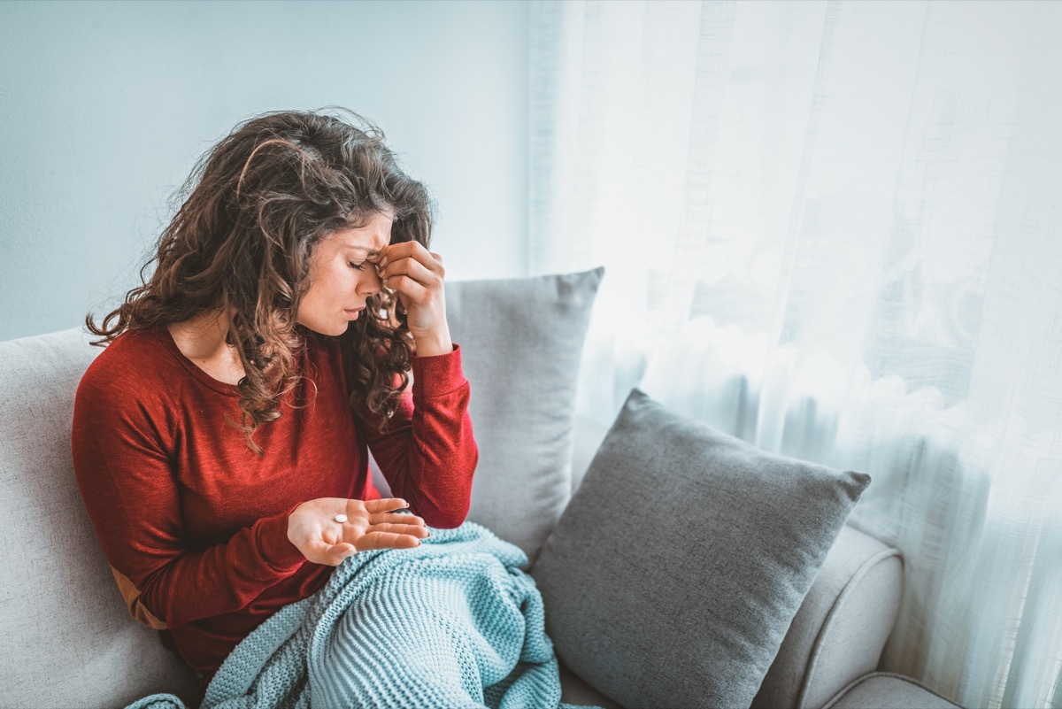 Close up image woman holding round pill and glass of still water taking painkiller to relieve painful feelings migraine headache, antidepressant or antibiotic medication, emergency treatment concept