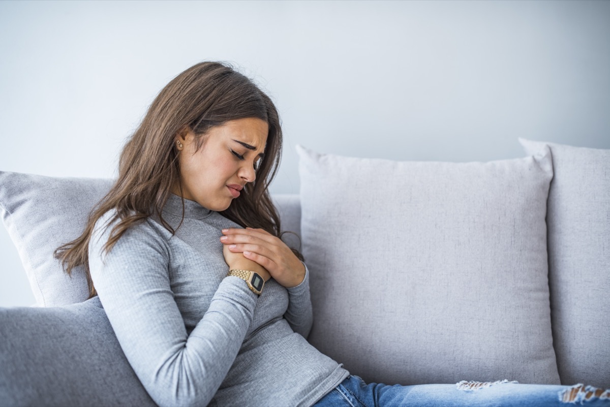 Woman holding hand to spot of pain area, chest