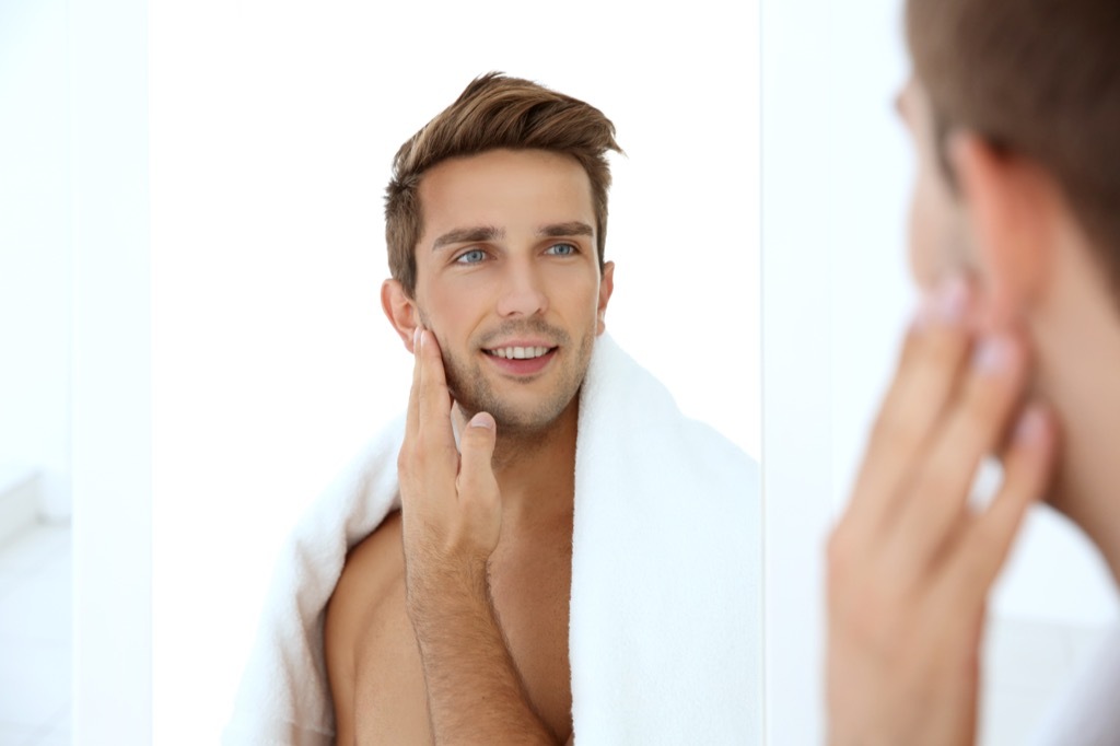 man with a towel looking at himself in the mirror