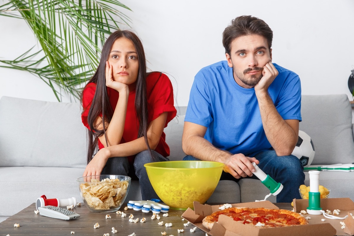 Woman and Man in relationship thinking on couch while watching TV