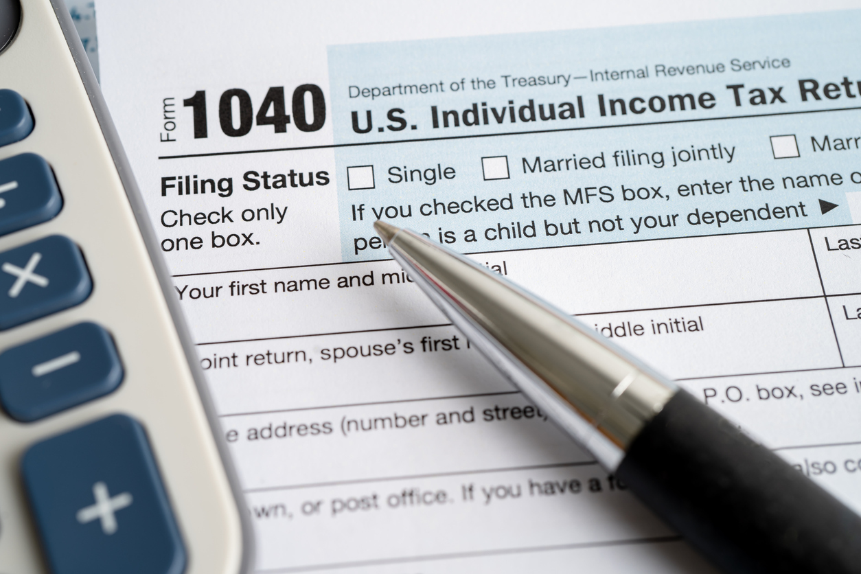 A close up of a form 1040 with a pen and a calculator