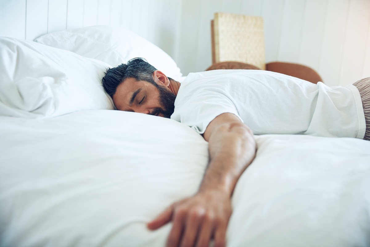 middle aged latino man sleeping on his stomach