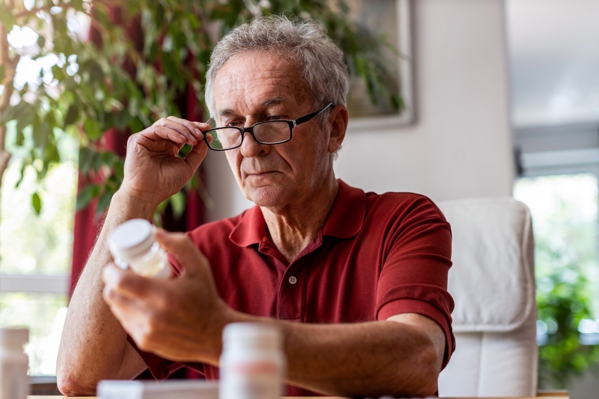 older man looking at supplements or medicine