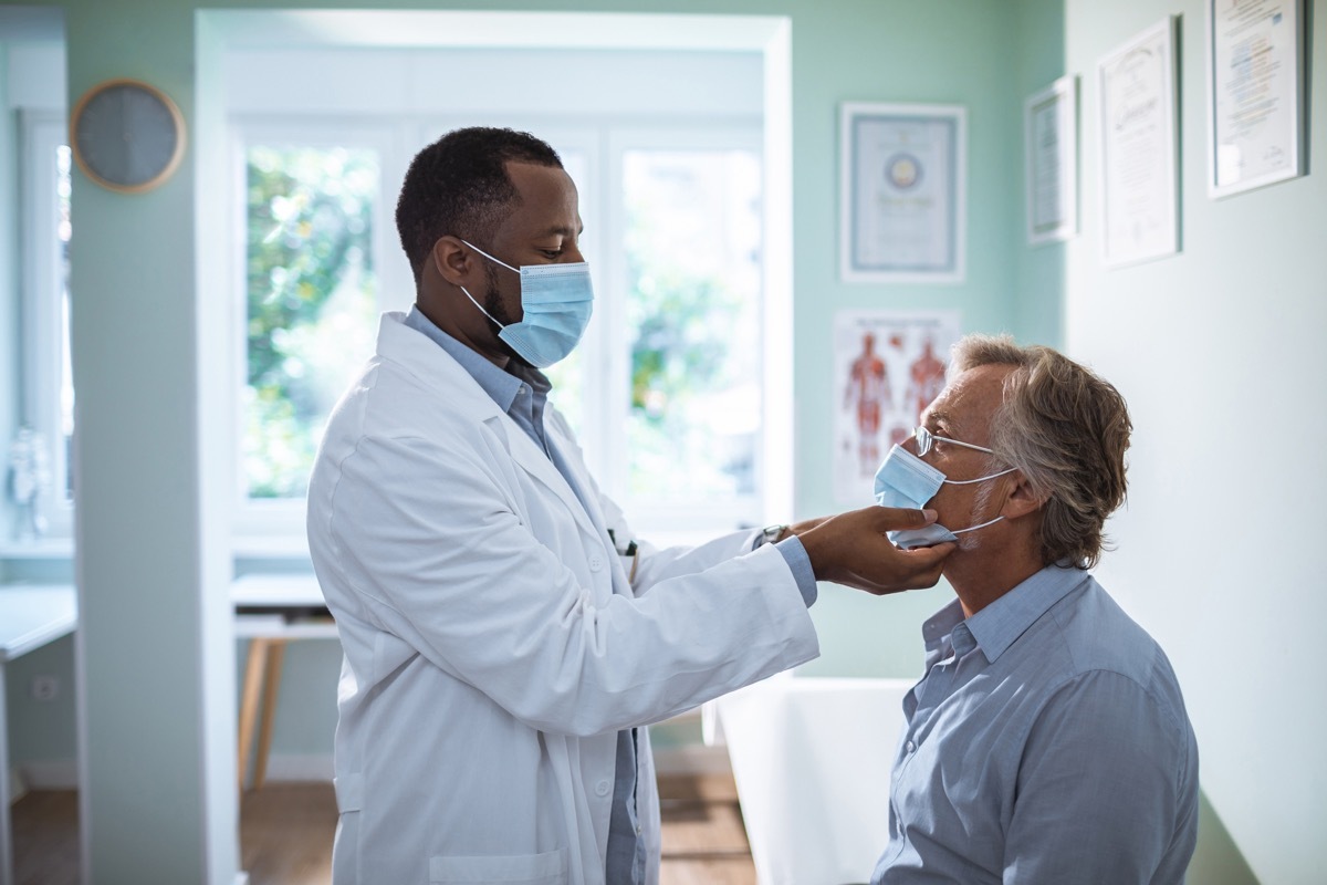 a male doctor checks a man's mouth