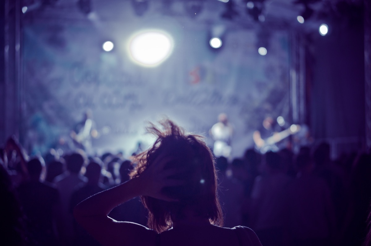 woman silhouette in a crowd at a concert in a vintage light, noise added