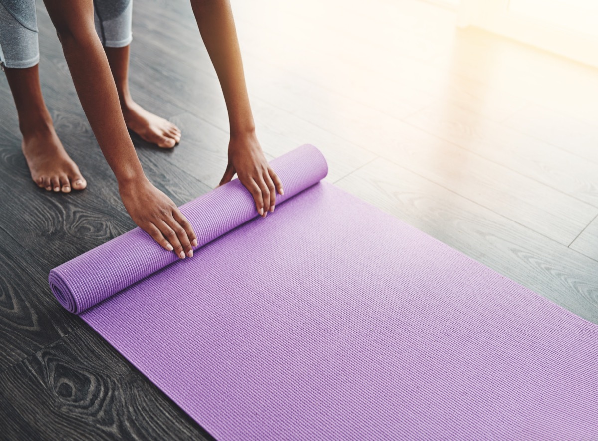 cropped shot of an unrecognizable woman rolling up her yoga mat