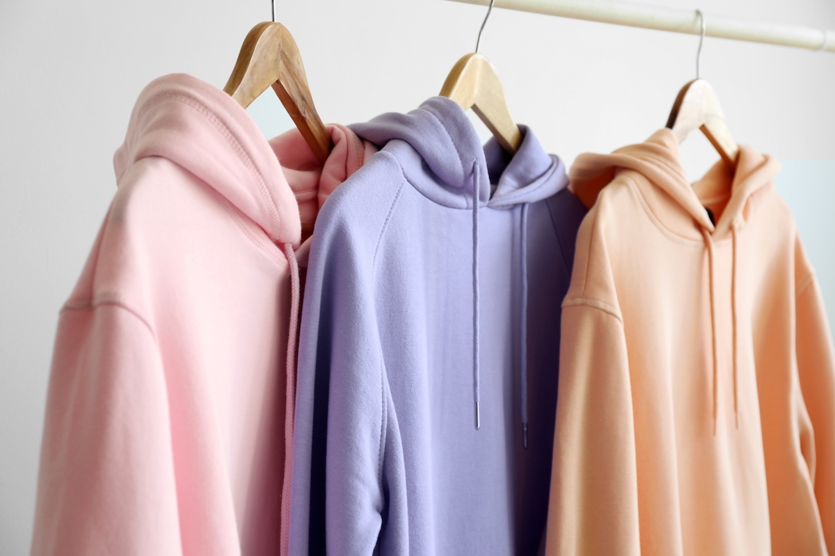 Pastel pink, purple, and peach hoodies hanging on a rack