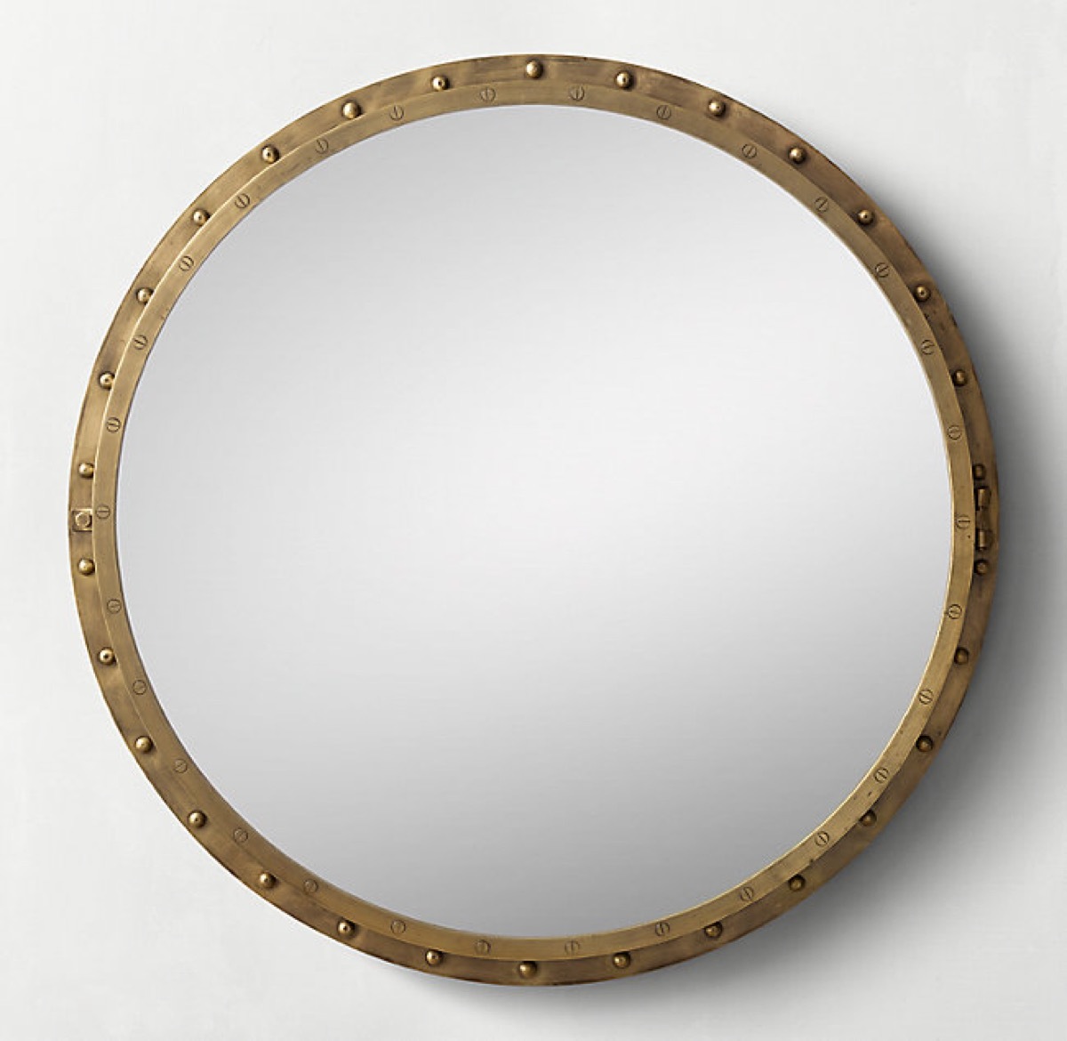 round gold mirror on white wall