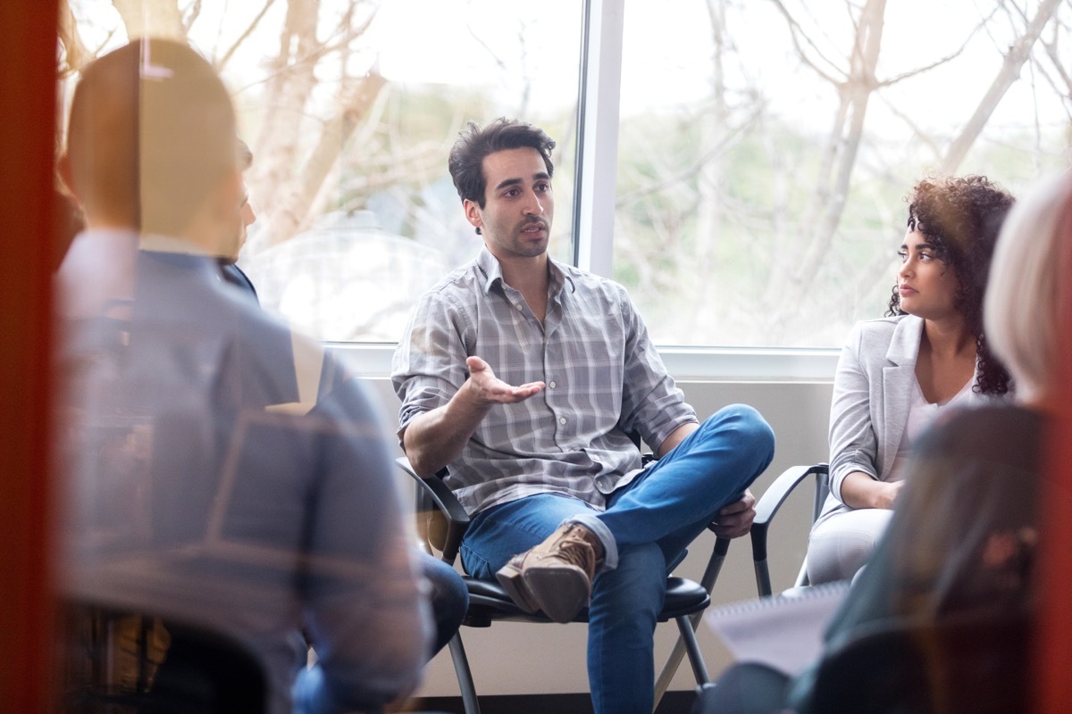 adult man making gestures while he talks to a group of people