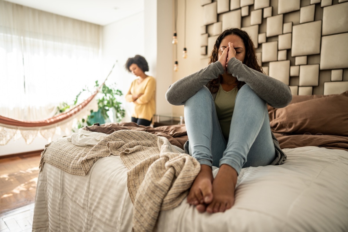 Emotional Person on Bed with Detached Person By Window