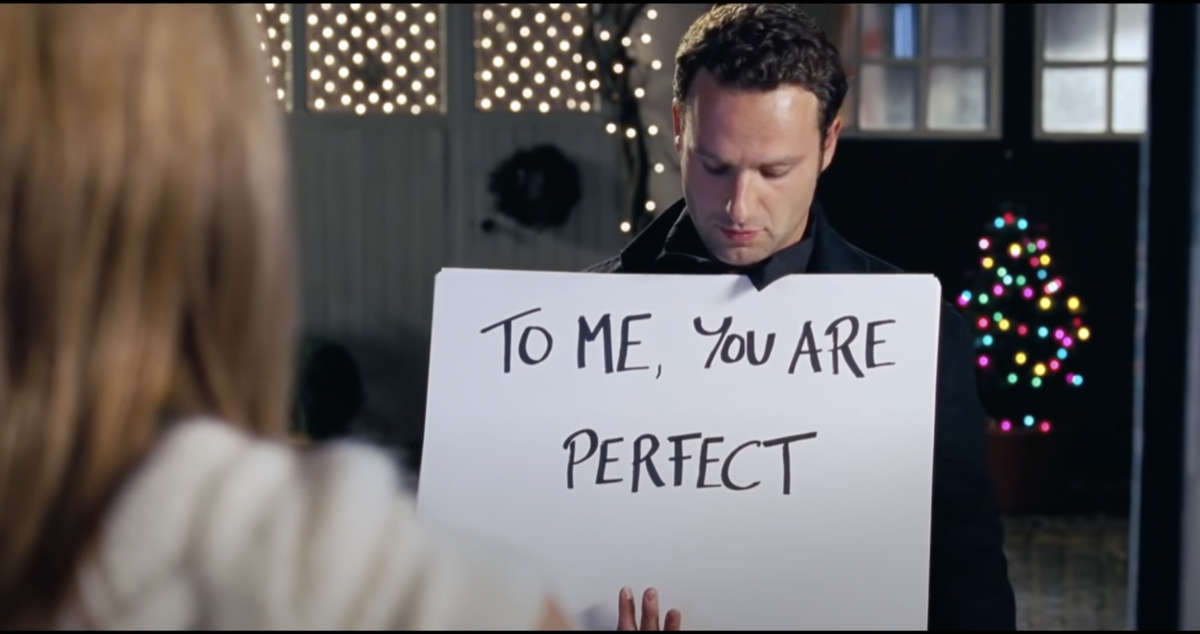 Screenshot of Love Actually scene with a sign that says to me you are perfect.