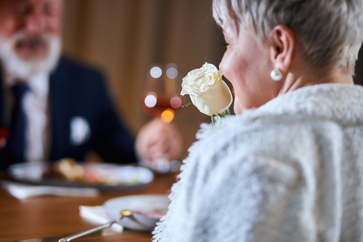 older woman smelling white rose