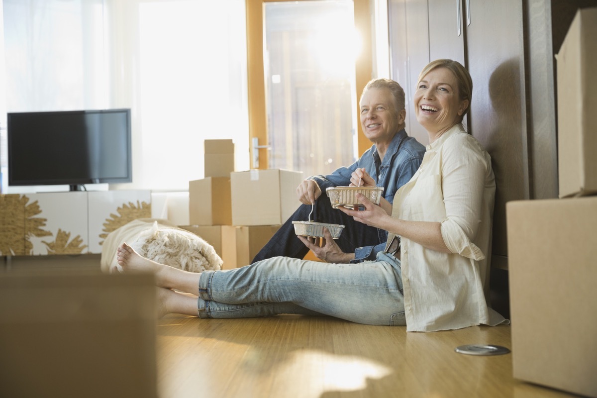 Couple eating take out food near moving boxes