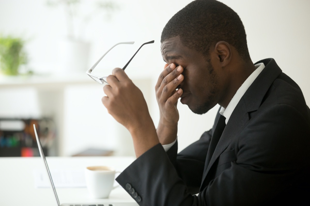 Young business man rubbing eyes at desk