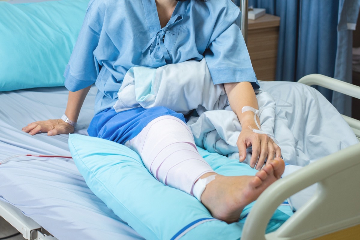 lderly old woman patient lying with bandage compression knee brace support injury on the bed in nursing ward hospital.