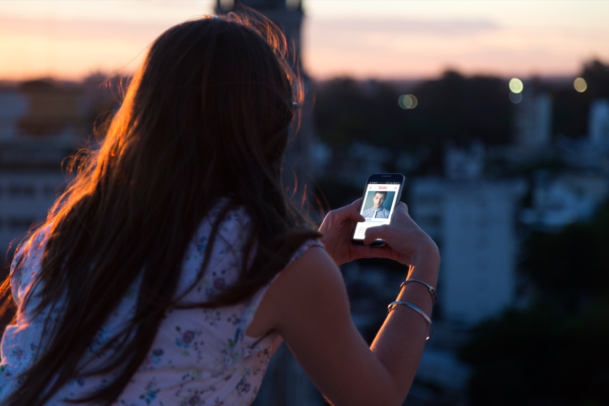 woman looking at her phone with the Tinder app on