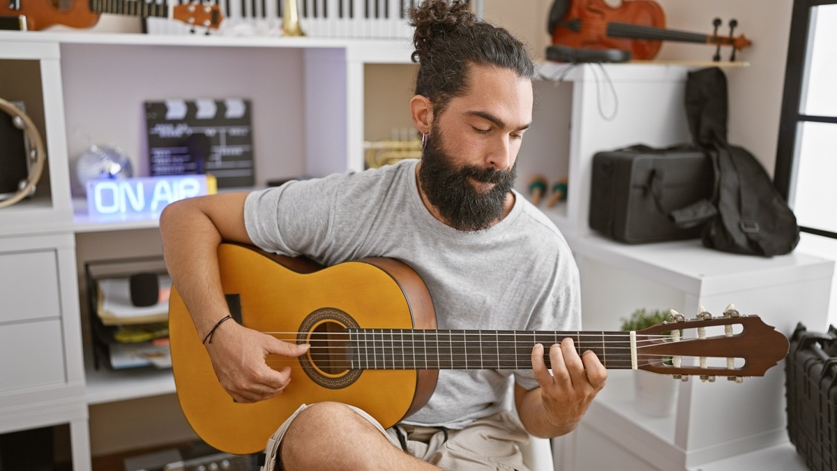 man playing guitar in his bedroom