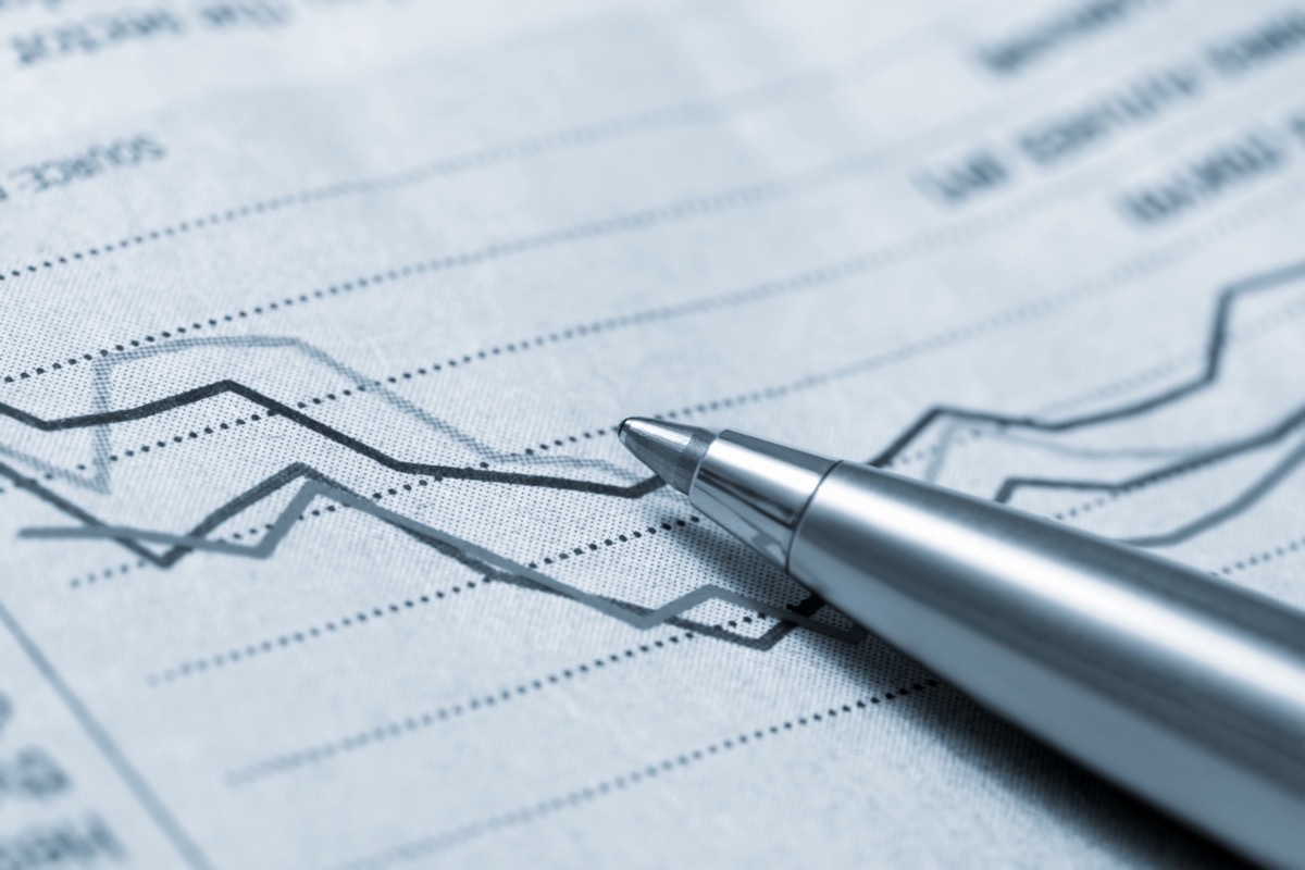 paper showing a graph indicating a decline in sales or profits with a silver pen on top