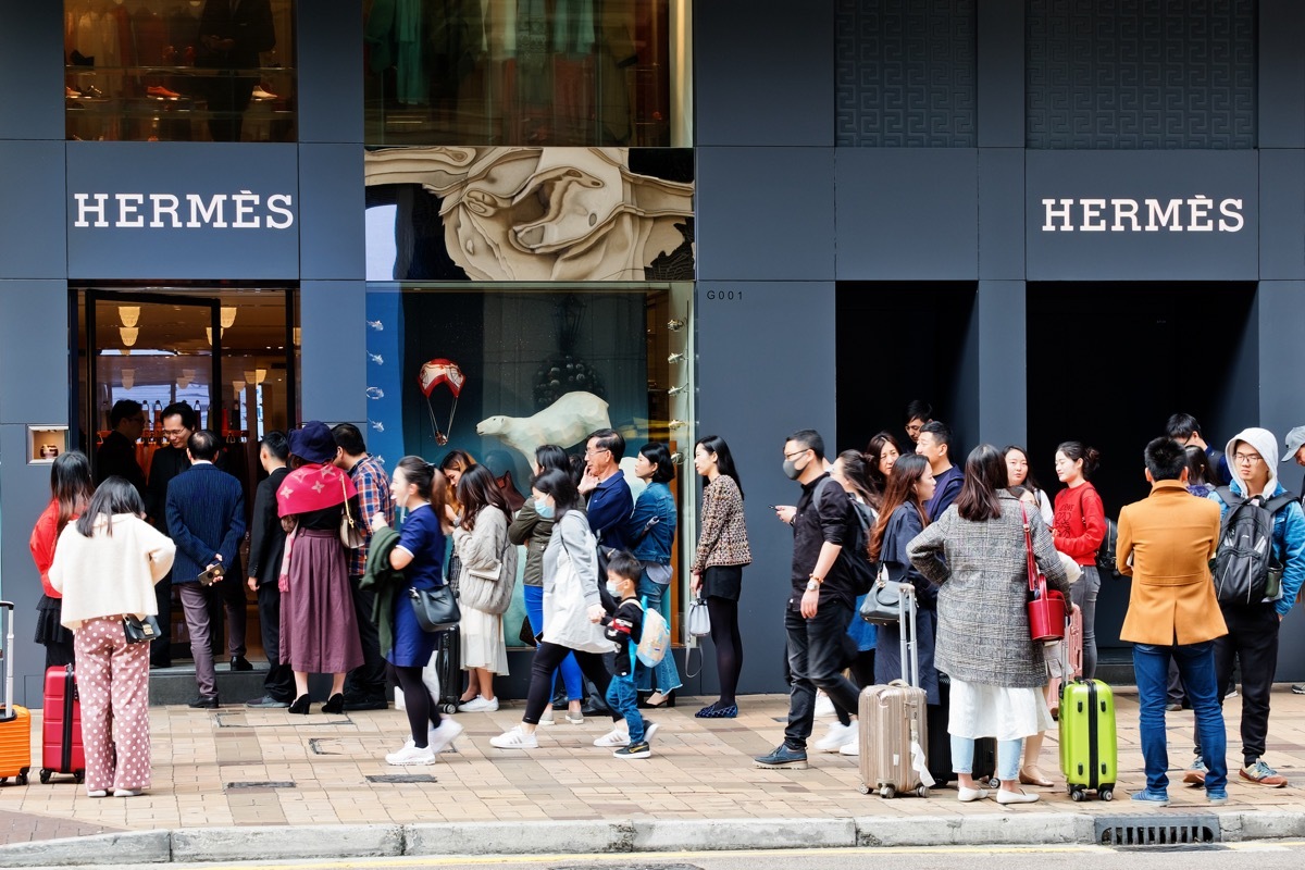 Tsim Sha Tsui, Hong Kong - 08 December, 2018 : People walk past the HERMES Shop in Canton Road, Hong Kong. People queuing outside and waiting to enter the store.